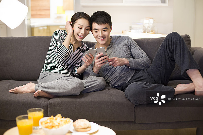 年轻情侣在客厅沙发上使用手机图片素材