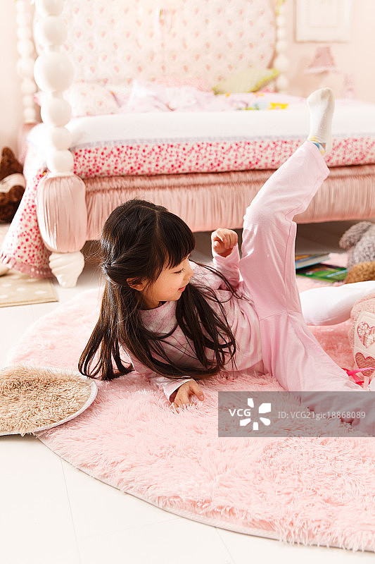 可爱的小女孩坐在地毯上玩耍图片素材