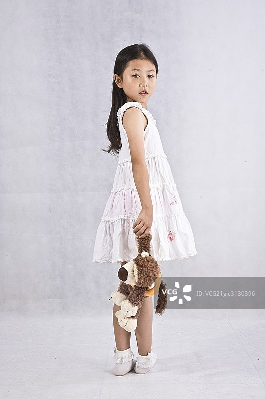 一个穿裙子拎毛绒玩具的小女孩图片素材