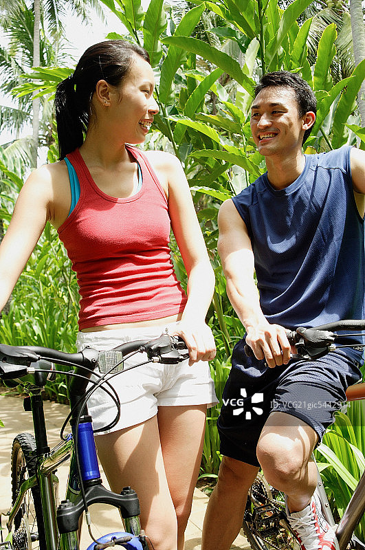 一对情侣骑着自行车，互相微笑着图片素材