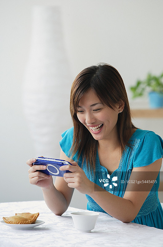 年轻女子在玩掌上游戏机图片素材