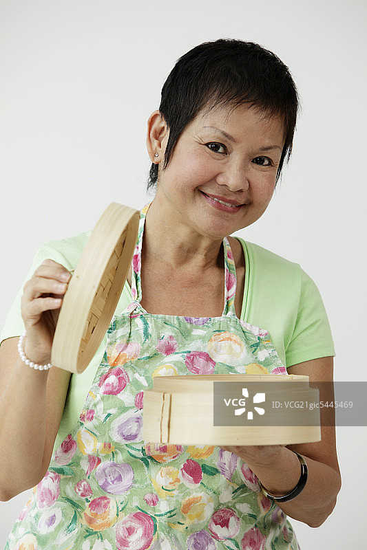 手持竹蒸笼的成熟中国女人图片素材