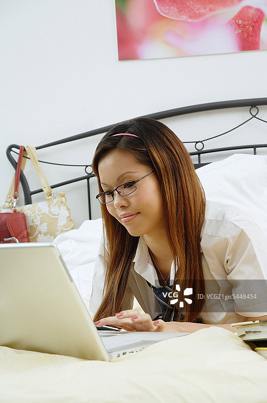 女孩躺在床上，用笔记本电脑图片素材
