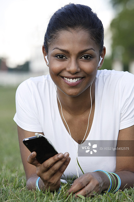 年轻女子躺在草地上听MP3图片素材