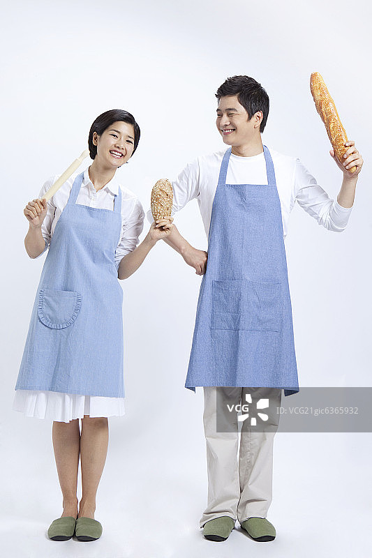 年轻夫妇穿着围裙，拿着面包图片素材