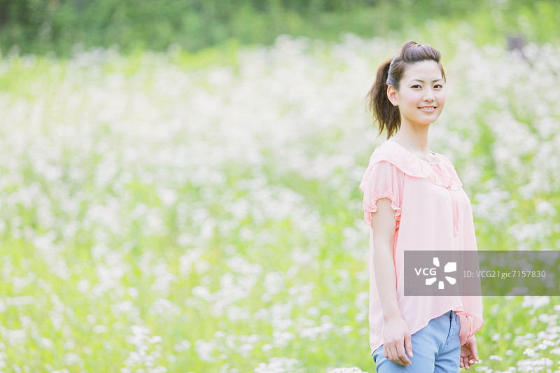 一个在草地上对着镜头微笑的日本女人图片素材