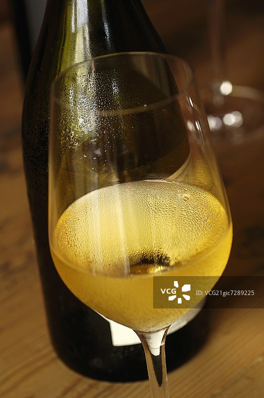 一杯白葡萄酒放在瓶子前面图片素材