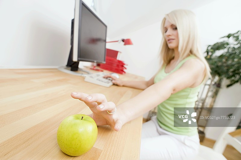 一个女人伸手去拿桌上的苹果图片素材