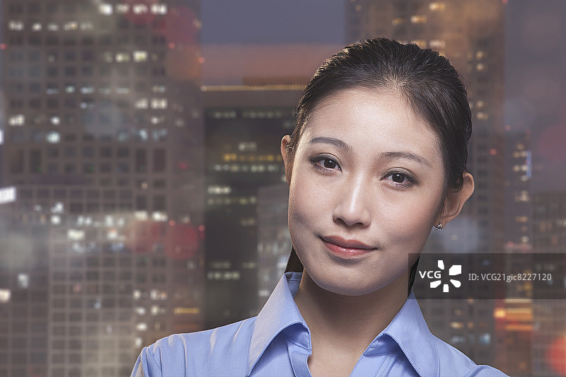 年轻微笑的女商人肖像，背景是北京的城市风景图片素材