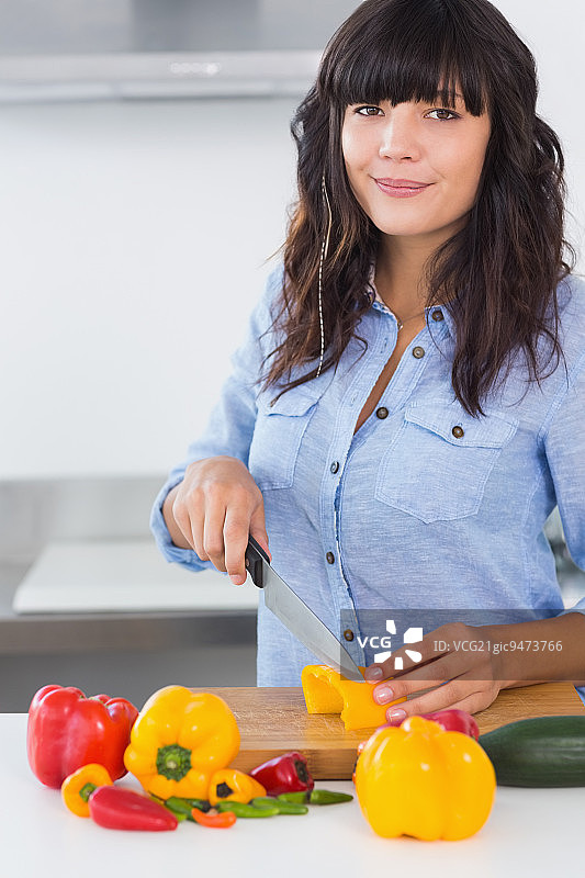 漂亮的黑发女子在厨房柜台切蔬菜图片素材