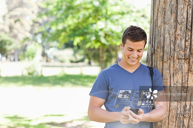 开朗英俊的学生在光明公园使用他的数字智能手机图片素材