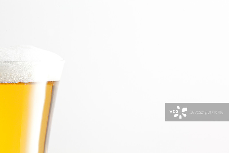 白色背景下充满泡沫和啤酒的玻璃杯图片素材