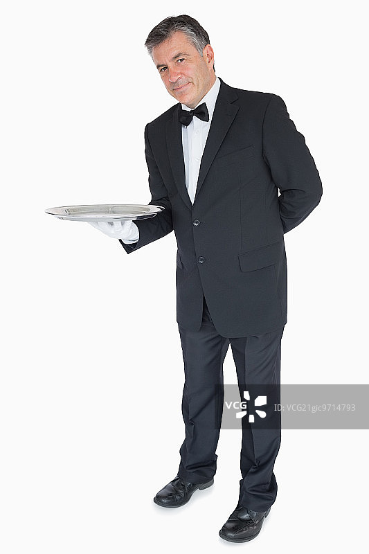 微笑的服务员，他的手在他的背后显示一个空托盘图片素材