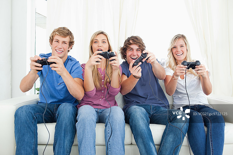一群快乐的朋友坐在沙发上玩电子游戏图片素材