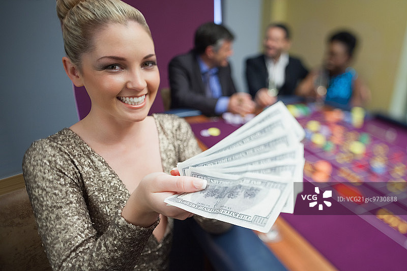 一个女人在赌场里拿着一堆钱图片素材