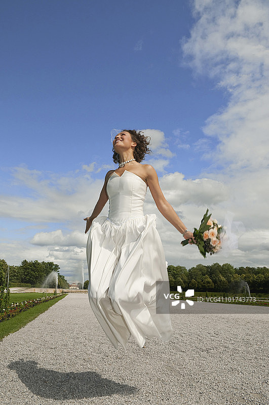 德国，巴伐利亚，新娘在公园的空中跳跃，微笑，肖像图片素材