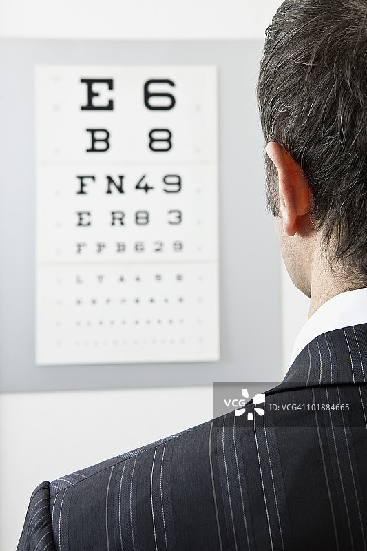 一个男人在看视力表，从肩膀看过去图片素材