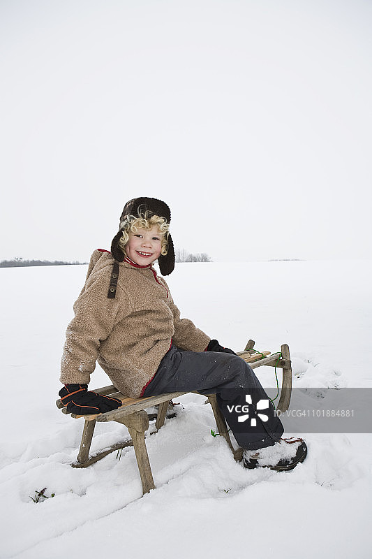 一个男孩坐在雪橇上图片素材