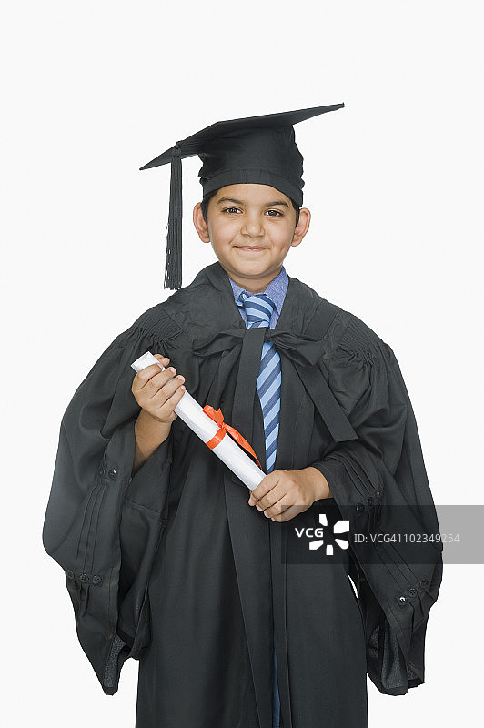 一个穿着毕业礼服拿着毕业证书的男孩的肖像图片素材