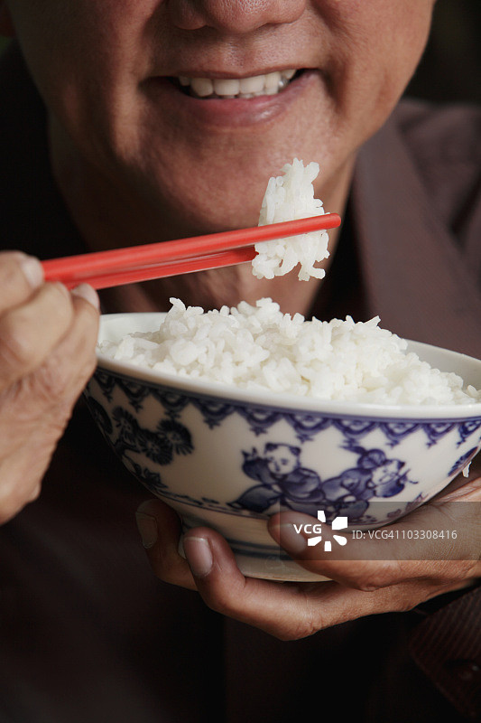 一个成熟的男人拿着筷子和一碗米饭图片素材