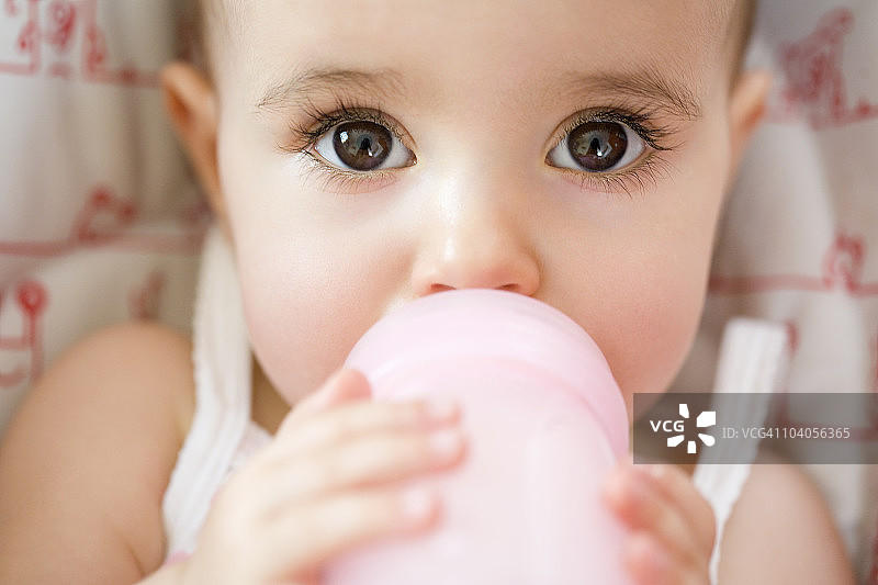小女孩用奶瓶喝水图片素材