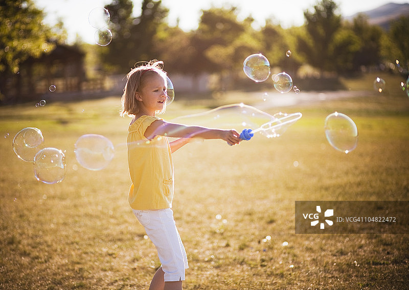 小女孩在公园里做大泡泡图片素材