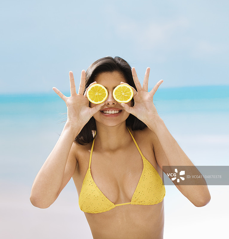 一个年轻女子拿着柠檬片放在眼前图片素材