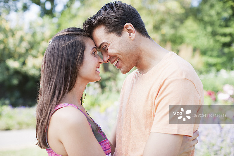 微笑的情侣在公园里拥抱图片素材
