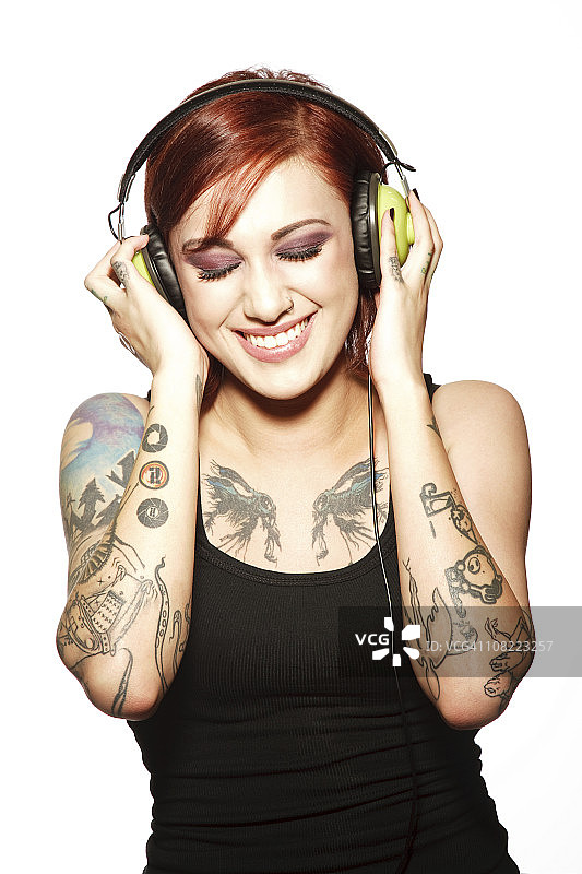 微笑的年轻女子纹身听耳机图片素材