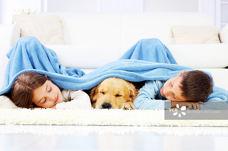 男孩，女孩和狗盖着毯子睡觉。图片素材