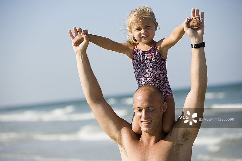 年轻的父亲肩上扛着女儿在海滩上图片素材