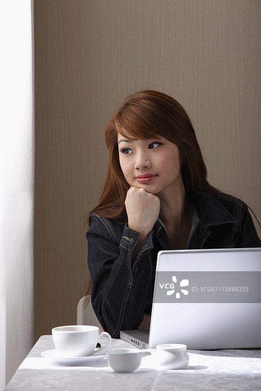 一个年轻女人正坐在桌子旁，拿着笔记本电脑图片素材