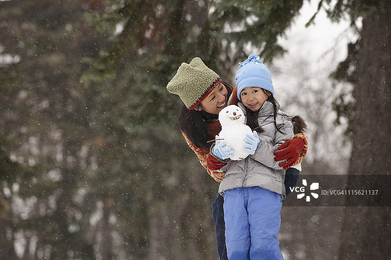 中国妈妈和女儿抱着小雪人图片素材