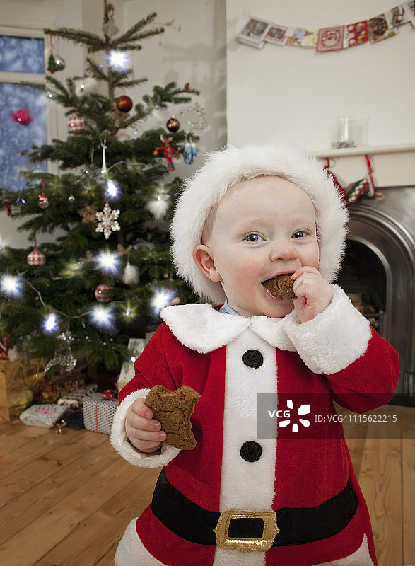 打扮成圣诞老人的婴儿正在吃饼干图片素材