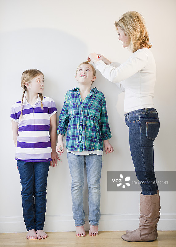 美国，新泽西州泽西城，母亲在测量女儿(8-11)的身高图片素材