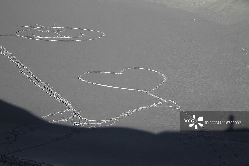 一个被脚印踩在雪地上的心形和笑脸图片素材