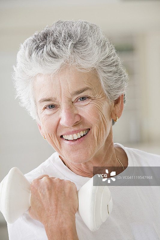 一位老年妇女举着哑铃锻炼的肖像图片素材