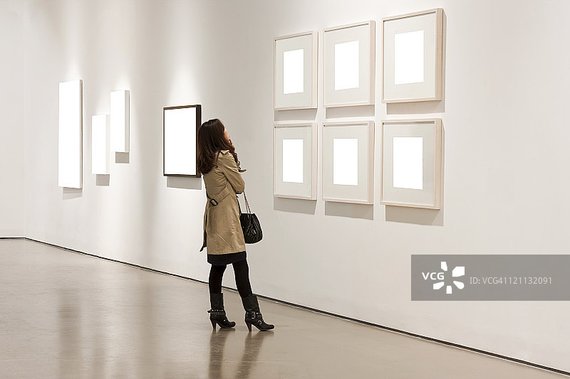 一位女士在画廊里看白色的镜框图片素材