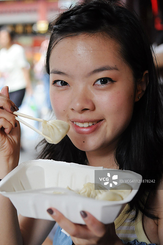 年轻的亚洲妇女正在吃蒸饺图片素材