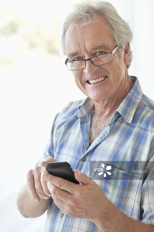 一个快乐的老男人用手机发短信的肖像图片素材