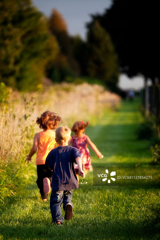 日落时分，孩子们在乡间的绿油油的小路上奔跑图片素材