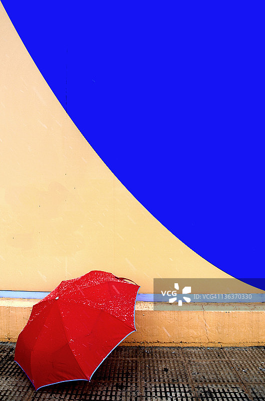 红色的伞在蓝色和黄色弯曲的墙上图片素材