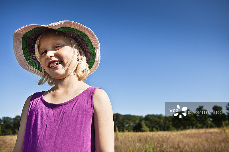 戴太阳帽的女孩在田野里微笑图片素材