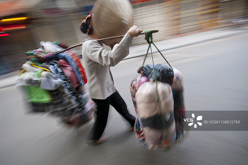 越南河内，一名当地妇女在搬运货物图片素材