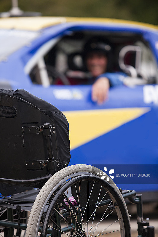 轮椅在为残疾人赛车改装的汽车前面图片素材