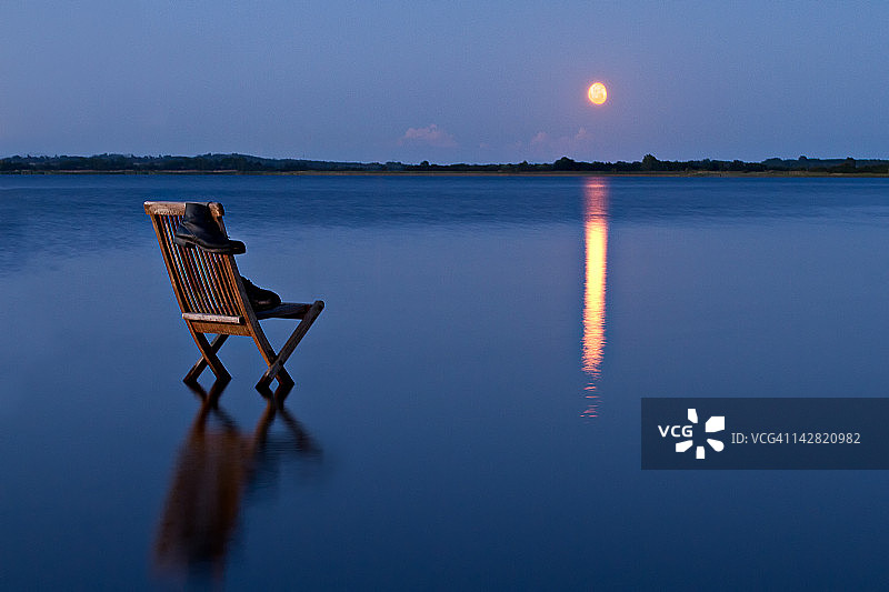 晚上坐在水中，天上挂着橙色的月亮图片素材