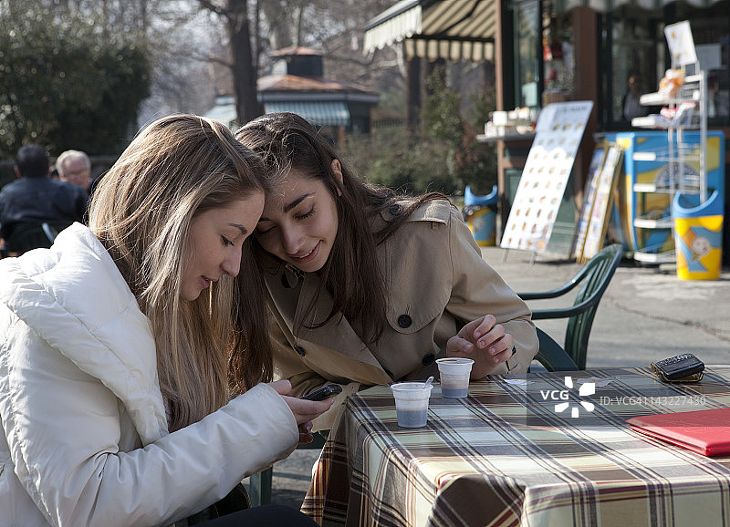 十几岁的女孩在户外咖啡馆查看短信图片素材