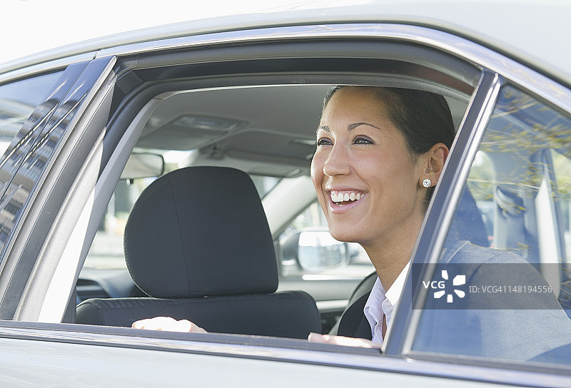 笑容可掬的西班牙裔女人坐在车后座图片素材