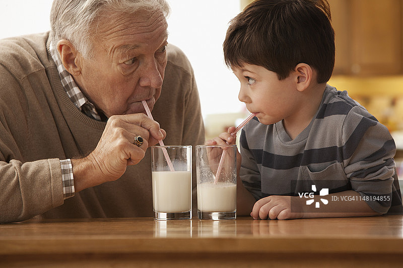 白人爷爷和孙子一起喝牛奶图片素材