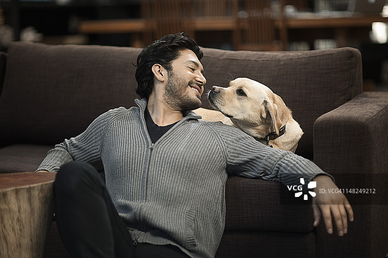 一名西班牙男子和一只狗坐在客厅里图片素材